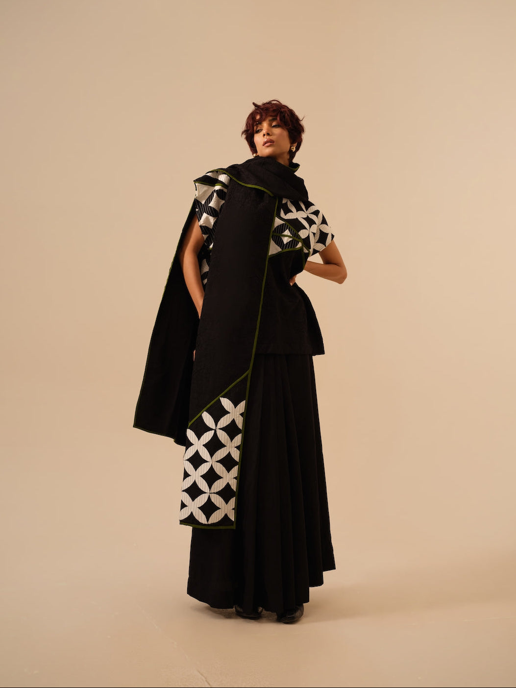 Woman wearing a black outfit with white geometric patterns on a beige background